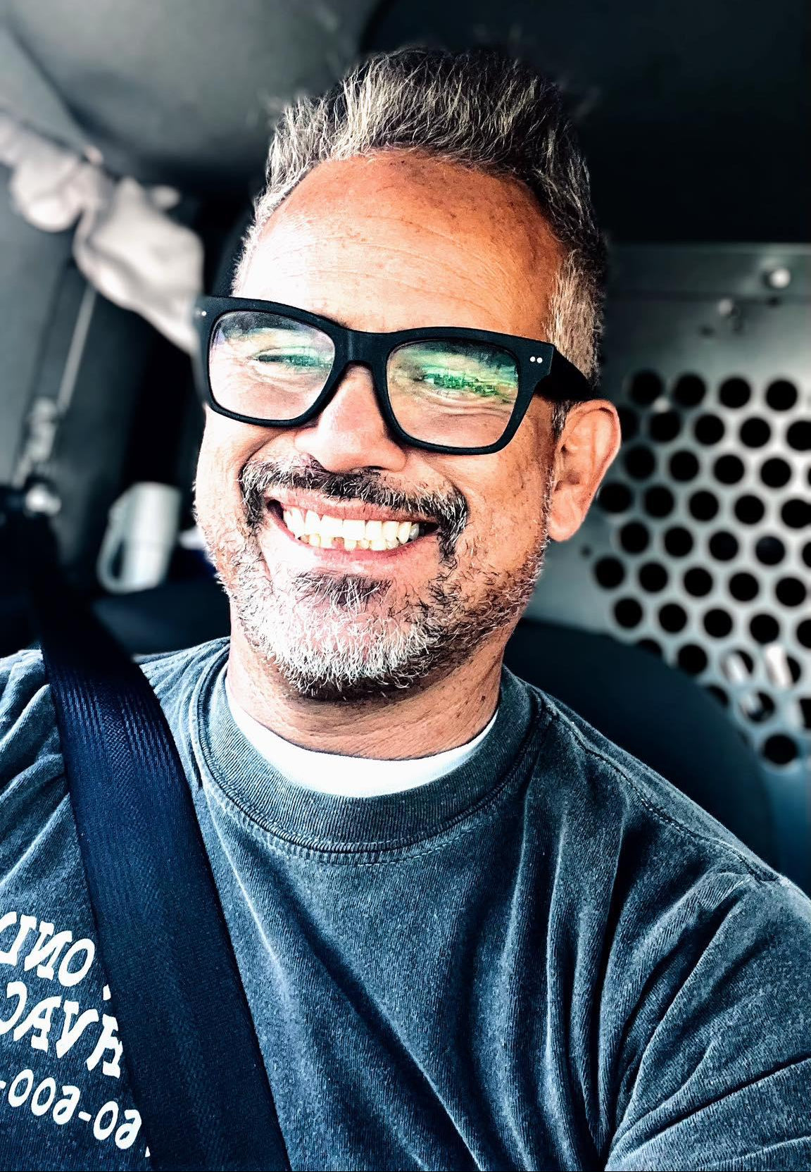 Man wearing glasses and a gray shirt inside a vehicle